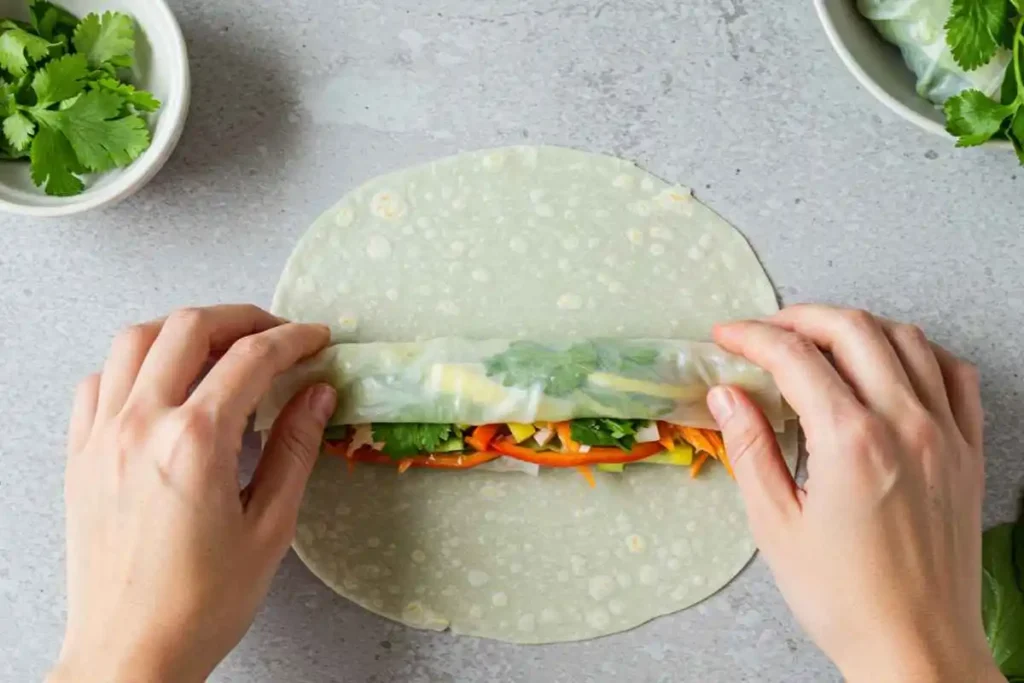  Hands rolling a spring roll with fresh ingredients for a perfect wrap.